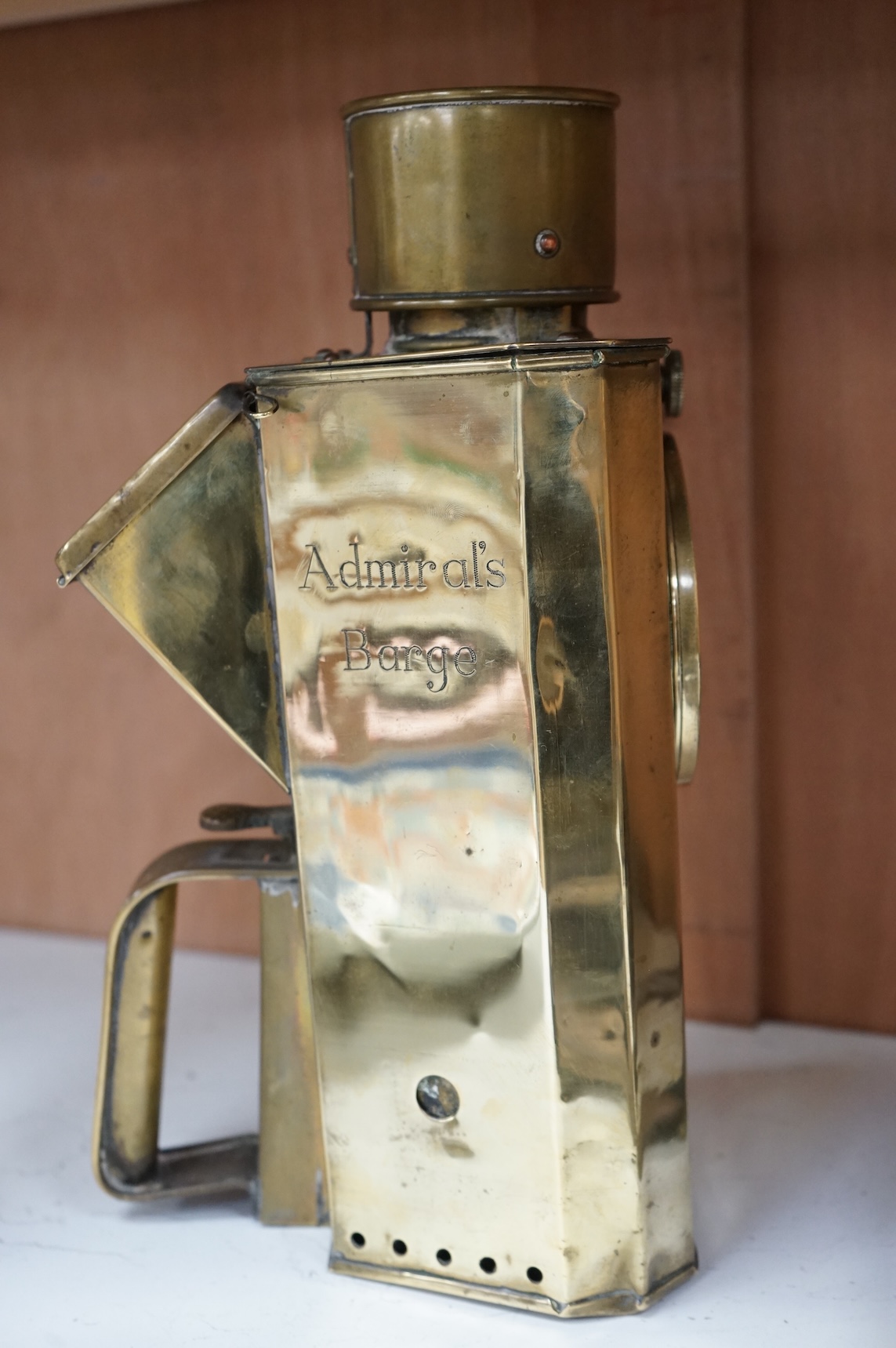 A naval brass Mitchell’s Patent morse code signalling lamp, numbered 24014 and dated 30 10 07, triangular body engraved ‘HMS Dreadnought’ to one face and ‘Admiral’s Barge’ to another, complete with burner and morse code